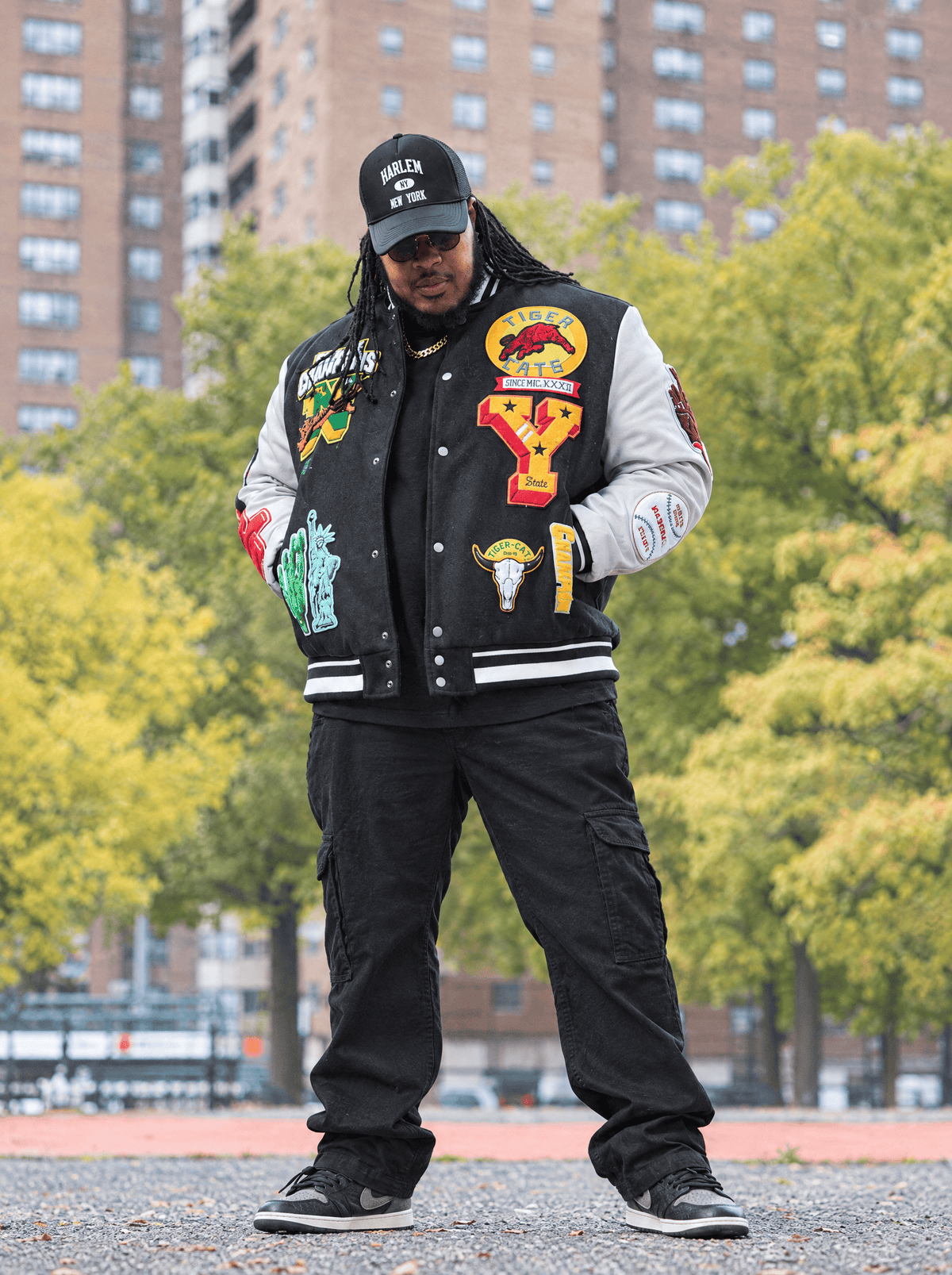 Big man in Harlem wearing Big Men's Xavier OG Cargo Pants in Black and the Empire City Varsity Jacket